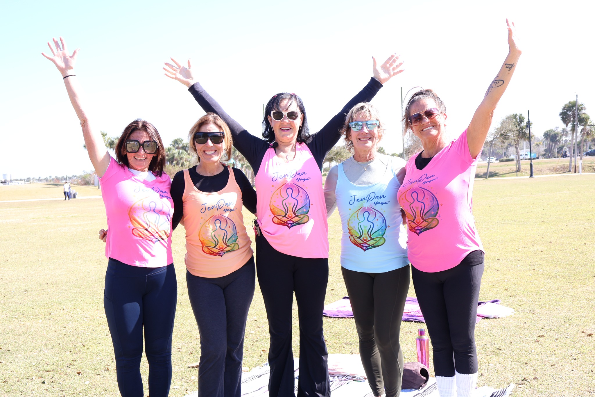 JenDan Yoga group outdoors with arms raised